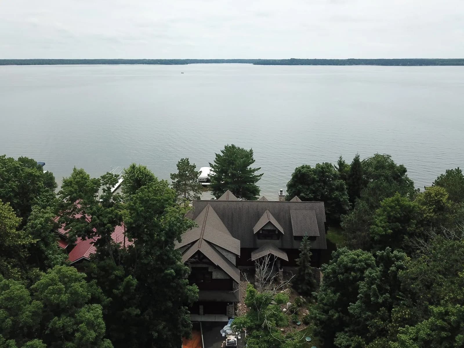 Aerial view of a lakefront estate with a new dark shingle roof overlooking a large lake