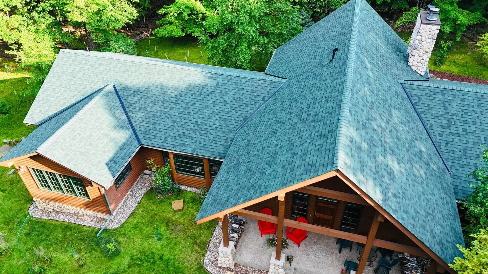 Aerial view of a log home with a teal green shingle roof