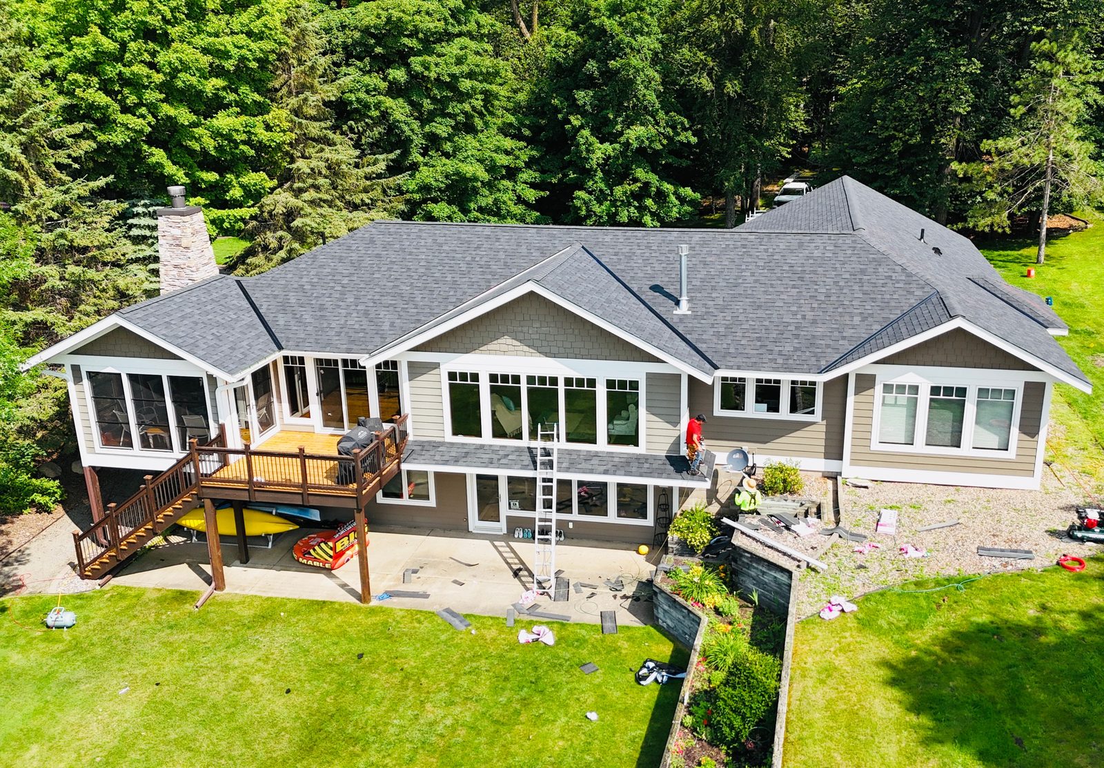 Aerial drone view of a craftsman home with a new gray architectural shingle roof and a large rear deck