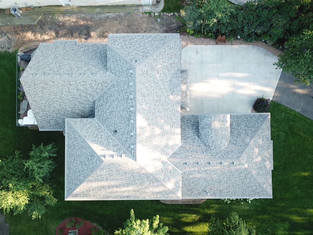 Straight overhead drone view of a freshly installed light gray architectural shingle roof