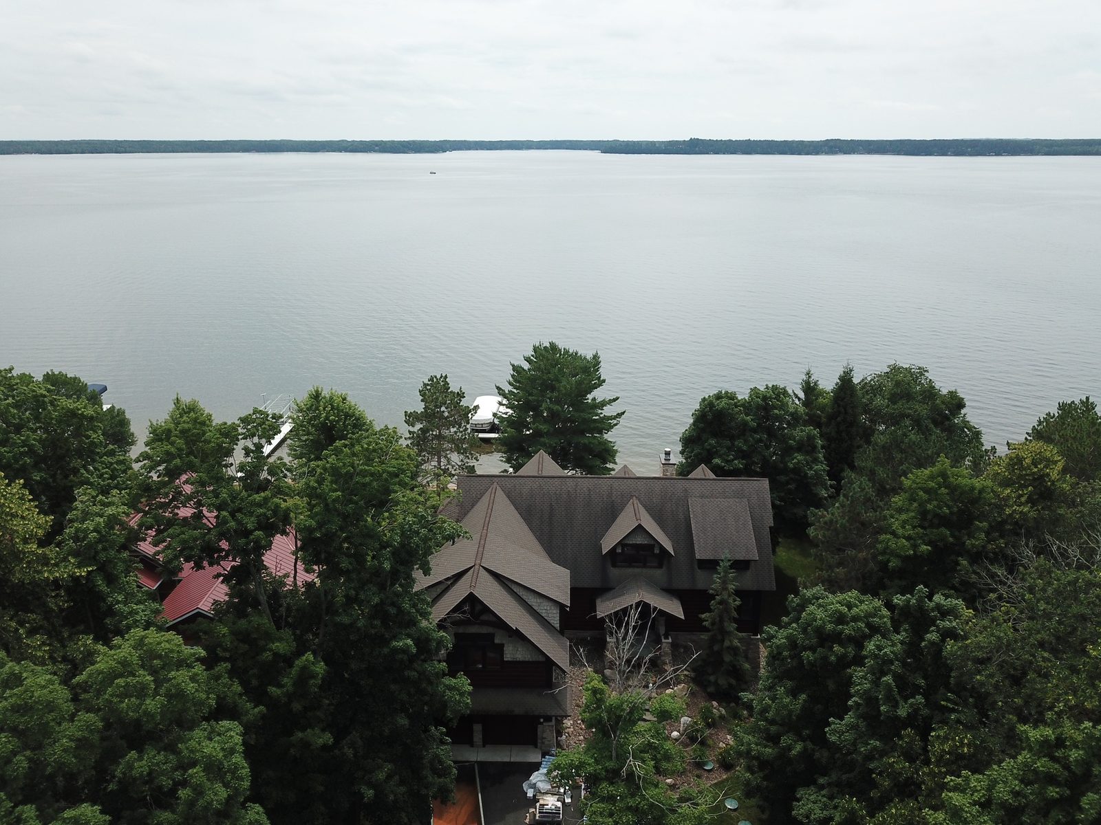 Aerial drone view of a lakefront estate with a new dark shingle roof overlooking a large lake