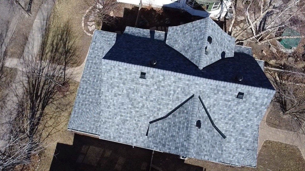 Aerial drone view of a two-story home with a newly installed gray architectural shingle roof