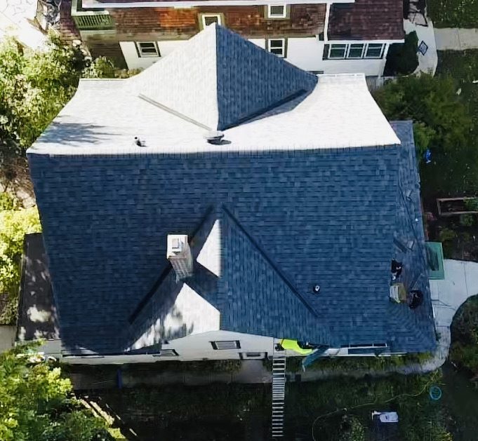 Aerial drone view of a completed roof replacement finished in blue-gray architectural shingle