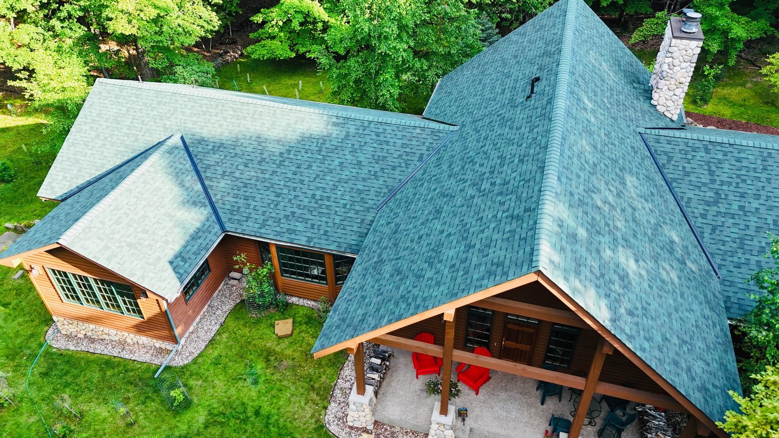 Aerial drone view of a log home with a teal green shingle roof