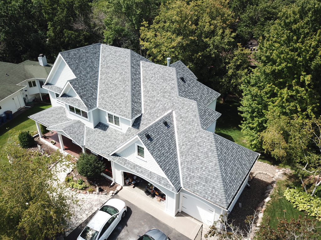 Aerial drone view of a white two-story home with a new gray shingle roof