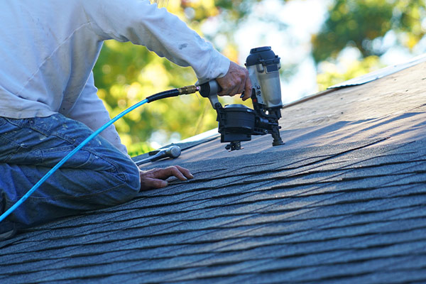 Roofing contractor reattaching shingles after a roof repair job in St Paul