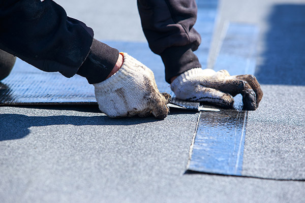 Roofer installing shingles on a roof that was damaged by a storm in St Paul