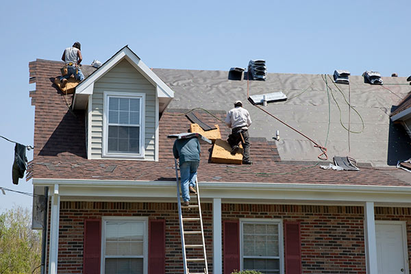 a group of men on a ladder on a roof completing a roof replacement project